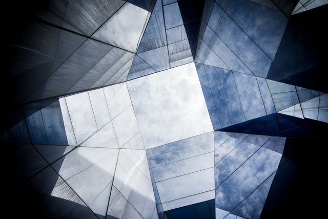 Modern architecture showcasing abstract geometric glass roof with sky reflections. Great for use in architectural magazines, design-focused blogs, urban landscape illustrations, and promotional materials for building and design businesses.