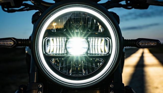 Motorcycle led headlight halo ring and projector beam illuminating road at dusk