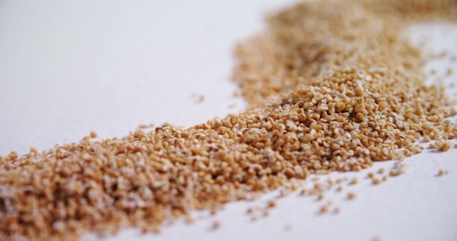Whole grain bran scattered on white surface, highlighting texture and nutritional elements. Great for illustrating topics related to healthy eating, nutrition, food ingredients, or dietary fiber.