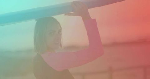 Young Surfer Holding Surfboard Overhead on Sunset Beach