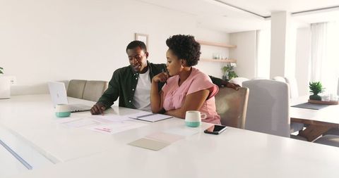 Two Friends Collaborating Over Documents at Home
