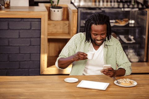 Smiling Man With Tablet and Coffee in Cozy Café Focused on Phone - Download Free Stock Videos Pikwizard.com