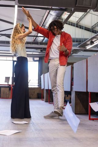 Excited colleagues celebrating successful achievement in contemporary office