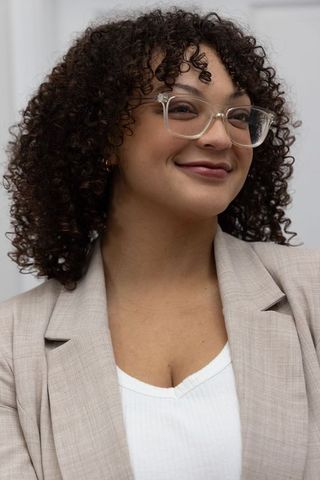 Confident african american professional woman smiling wearing clear glasses and tan blazer