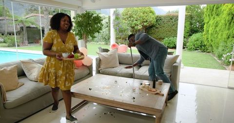 Couple Tidying Up After Party at Home, Embracing Teamwork