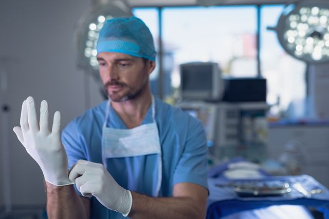 Male surgeon wearing surgical gloves in operation room at hospital