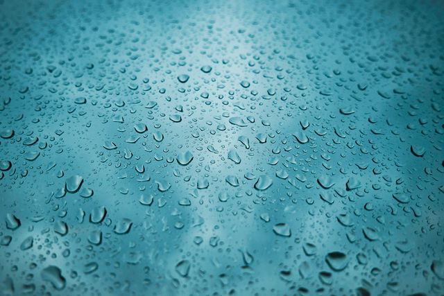 Depicting water droplets on a glass surface with a blue background, this image captures freshness and moisture. Ideal for themes related to weather, climate, freshness, purity, or hydration. Useful in designing advertisements, blogs, and social media posts about water conservation, rainy seasons, or refreshing beverages.