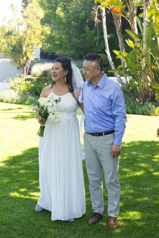 Senior asian groom and bride smiling holding bouquet in tropical garden wedding