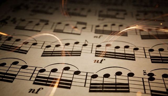 Vintage sheet music glowing with golden light trails closeup on textured parchment for music concept