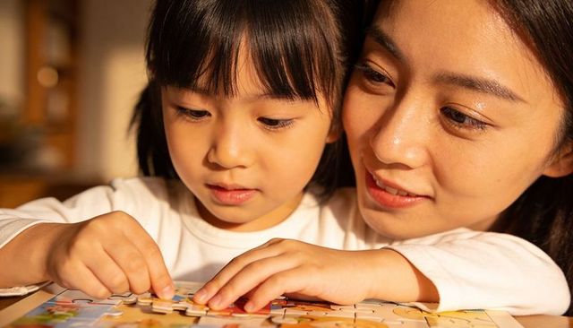 Mother and daughter assembling jigsaw puzzle sharing warm close-up bonding moment at home
