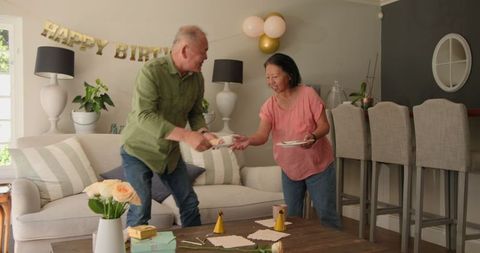 Elderly couple exchanging gift smiling on birthday celebration at home