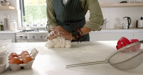 Confident young chef kneading dough in modern kitchen