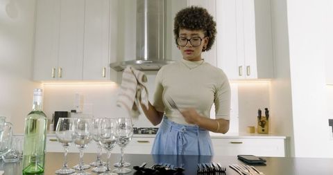 Woman preparing for event in kitchen with glassware