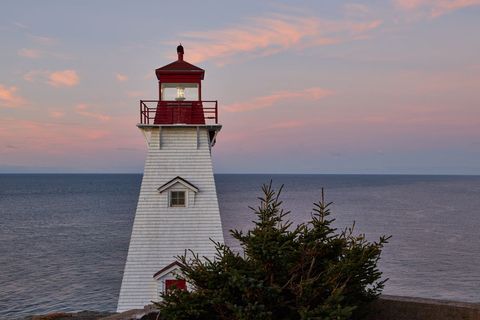 Sunset illuminating red-top lighthouse by the sea