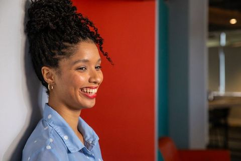 African american professional woman smiling, leaning in colorful office coworking headshot