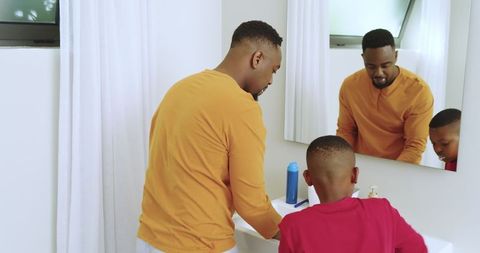 Father and son practicing hand hygiene in modern bathroom