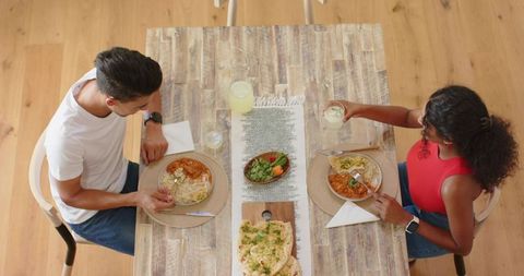 African american couple sharing homemade curry and naan at rustic wooden dining table