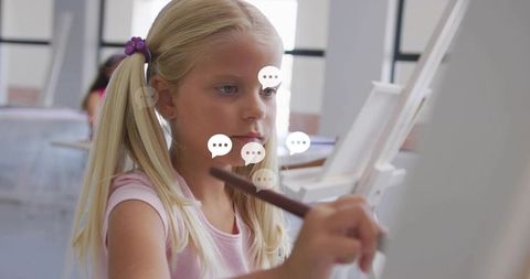 Blonde girl painting on canvas in classroom art studio focusing on creativity and learning