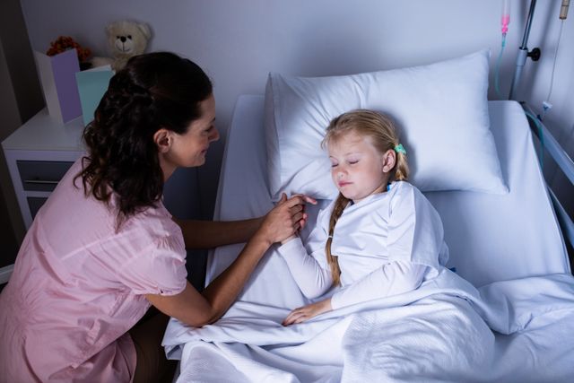 Depicts a female doctor showing compassion and providing comfort to a young patient in a hospital bed. Suitable for use in healthcare articles, medical brochures, pediatric care promotions, and websites emphasizing patient care and recovery.