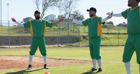 Amateur baseball team stretching arms during warmup on sunny neighborhood field