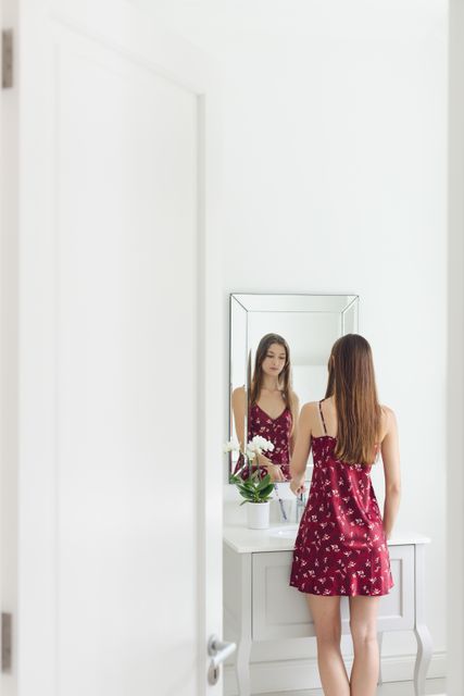 Beautiful woman standing in front of bathroom mirror in a comfortable home