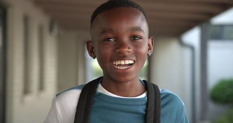 Joyful african american student in outdoor corridor with backpack