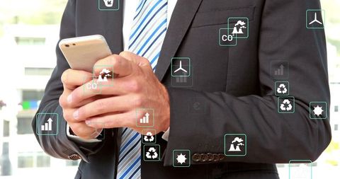 Businessman holding smartphone tapping screen with floating green finance and eco icons
