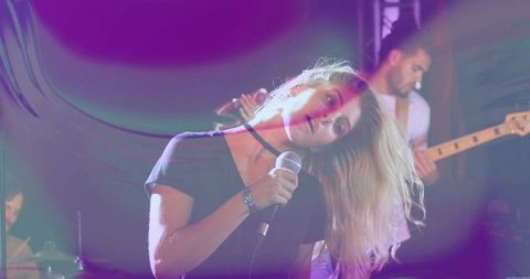 Blonde Lead Singer Leaning Head While Singing Into Wired Microphone Under Neon Stage Lights