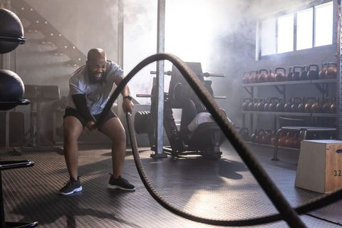 African american men training with battle ropes, pushing intensity in industrial gym
