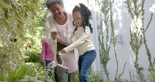 Grandmother assists granddaughter while watering plants in a lush garden. Perfect for depicting family bonding, gardening tips, sustainable living, spring and outdoor fun.