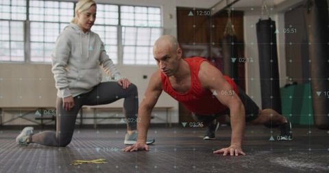 Male athlete performing plank while coach guides form during gym strength training session