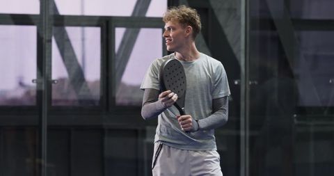 Male padel player holding racket in modern indoor court