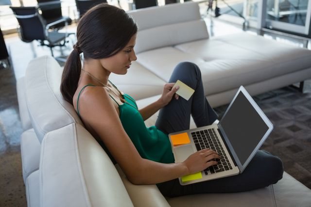 Young businesswoman using laptop while relaxing on sofa at office