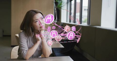Contemplative asian woman gazing at pink augmented reality network hologram in modern cafe lounge