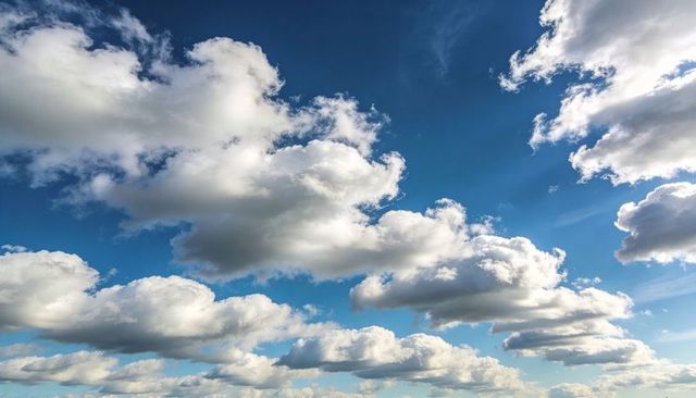 Sunlit cumulus cloudscape over rural horizon with dramatic sunbeams and deep blue sky