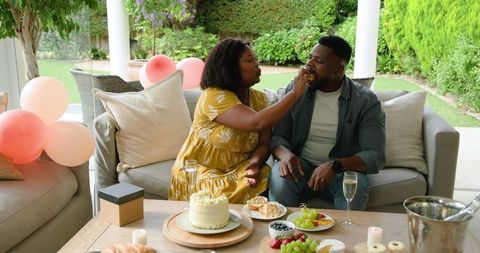 African american couple celebrating with cake at outdoor garden party