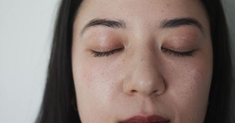Young woman resting with eyes closed, close-up showing natural skin texture and eyelashes