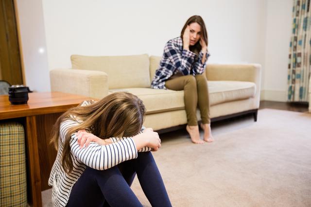 Upset mother and daughter sitting in living room at home