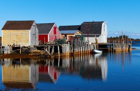Colorful Fishing Shacks Reflecting on Calm Coastal Harbor in Bright Morning Light
