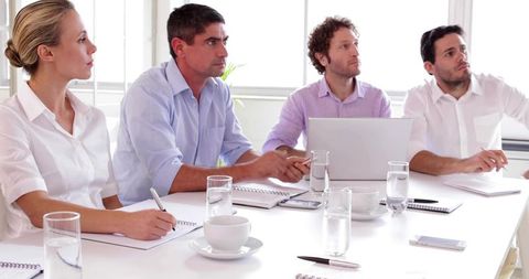 Business team collaborating around laptop during focused meeting in bright modern office