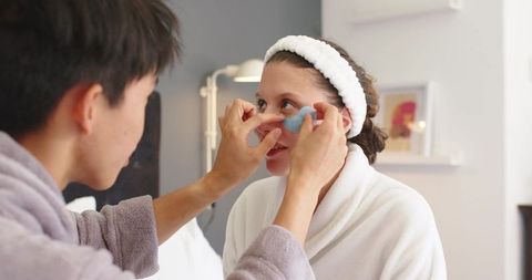 Couple applying under-eye gel patches during morning skincare routine in cozy bedroom