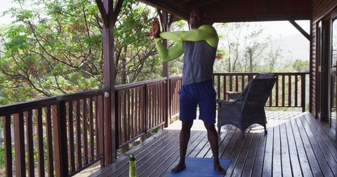 Senior Man Practicing Yoga on Cabin Veranda Surrounded by Nature