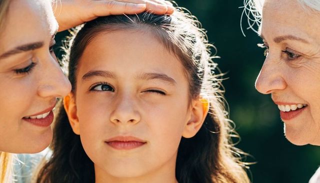 Playful multigenerational family portrait with winking child and sunlit backlit hair