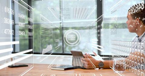 Analyst Using Laptop with Augmented Reality Interactive Data Dashboards in Modern Workspace