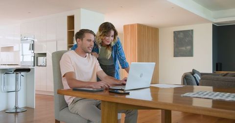 Couple Collaborating on Laptop in Modern Kitchen Setting