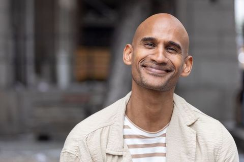 Bald african american man smiling close-up in beige blazer and striped tee urban headshot
