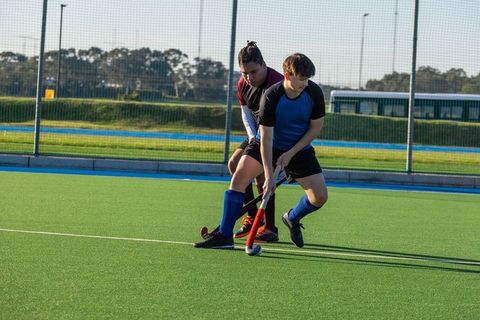 Two male field hockey players competing on synthetic field