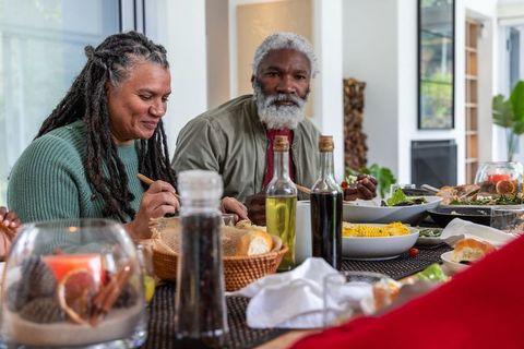 African american senior couple sharing bread and dinner at modern home dining table