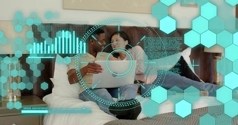 Couple browsing laptop on bed with augmented reality hud overlay and digital data graphics