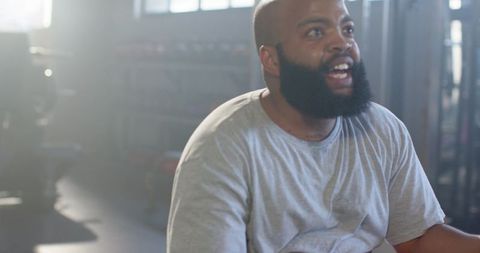 African American man catching breath after intense workout standing near weight racks